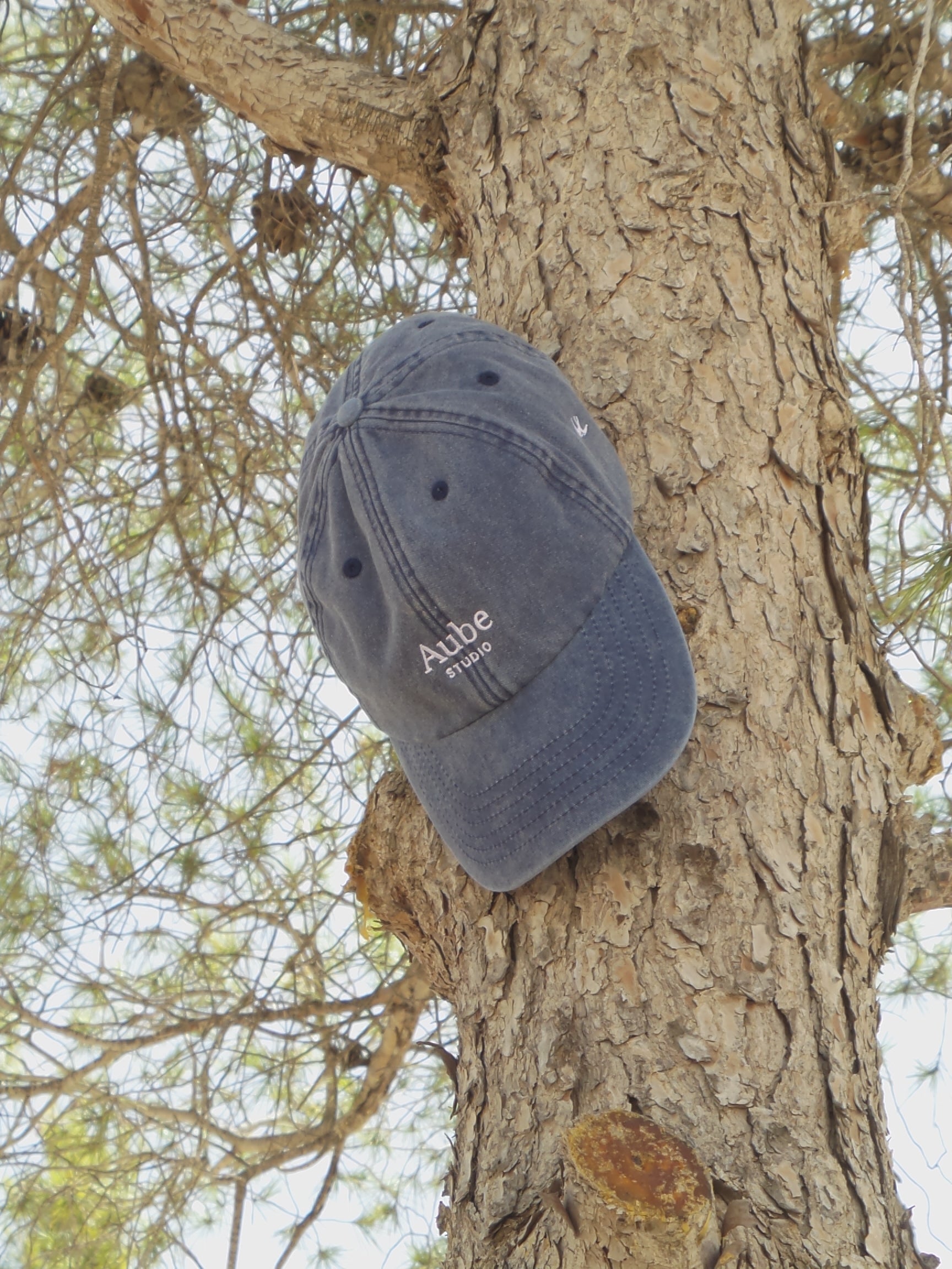 Aube Baseball Cap White Embroidery by Aube Studio in Vintage Light Denim - Front hanging down on tree view - Unisex oversized fit - Aube Studio